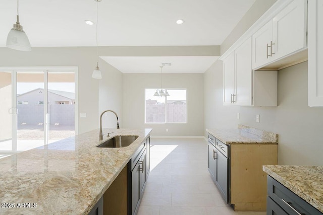 kitchen featuring light stone countertops, sink, decorative light fixtures, and white cabinets