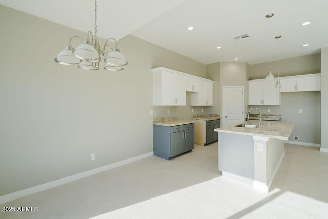 kitchen with white cabinetry, sink, hanging light fixtures, and a kitchen island with sink