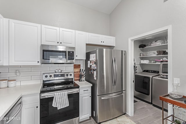 kitchen with washing machine and clothes dryer, white cabinets, decorative backsplash, and appliances with stainless steel finishes