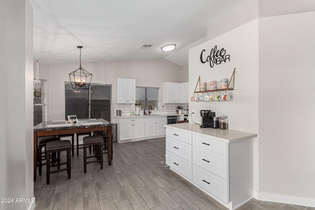 kitchen featuring hanging light fixtures, white cabinetry, backsplash, light hardwood / wood-style flooring, and a notable chandelier