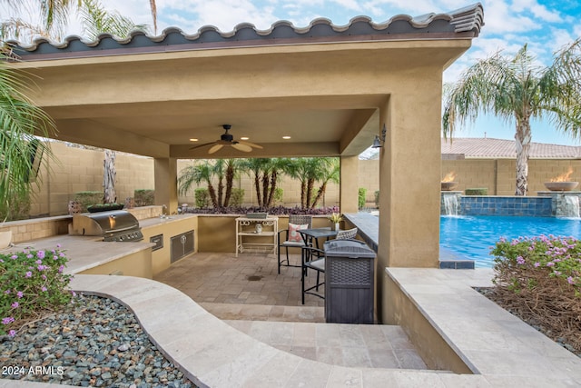 view of patio featuring pool water feature, ceiling fan, area for grilling, a fenced in pool, and grilling area