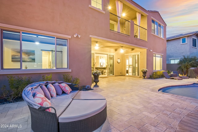 patio terrace at dusk featuring a balcony and an outdoor living space