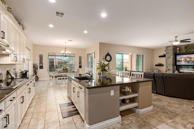 kitchen featuring white cabinets, ceiling fan with notable chandelier, a wealth of natural light, and a kitchen island with sink