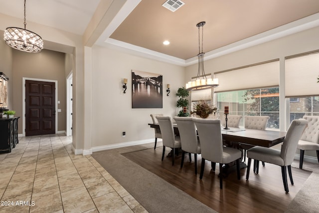 dining area with light tile floors, a chandelier, and a tray ceiling