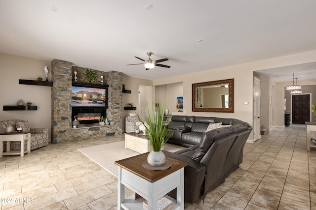 tiled living room with ceiling fan with notable chandelier and a fireplace