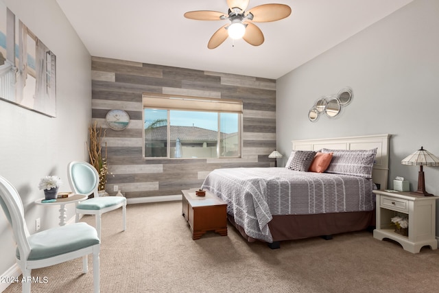 carpeted bedroom featuring wooden walls and ceiling fan