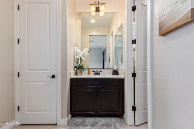 bathroom with an inviting chandelier, tile flooring, and large vanity