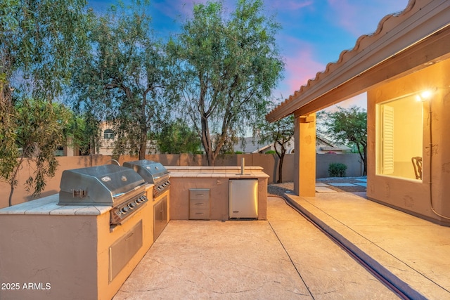 19275 N 88th Way, Scottsdale, AZ 85255 - patio terrace at dusk with a fenced backyard, a patio area, and exterior kitchen