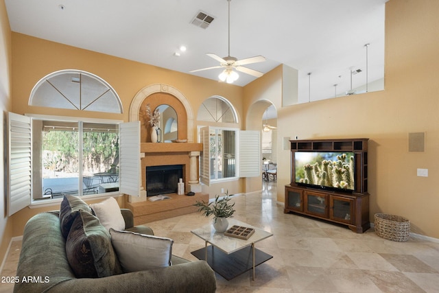 19275 N 88th Way, Scottsdale, AZ 85255 - living room featuring a towering ceiling, ceiling fan, a fireplace with raised hearth, and arched walkways