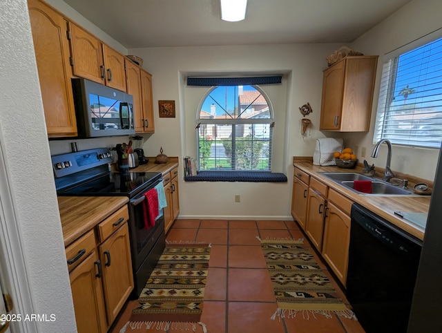 kitchen featuring black appliances, dark tile patterned floors, light countertops, and a sink