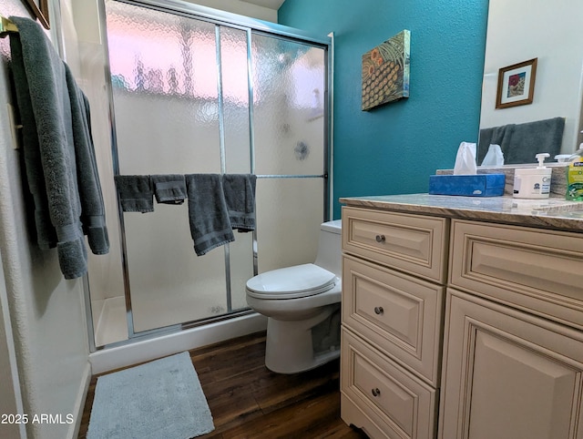 bathroom featuring a stall shower, toilet, vanity, and wood finished floors