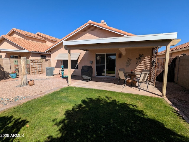 rear view of property featuring a tile roof, stucco siding, a lawn, a fenced backyard, and a patio