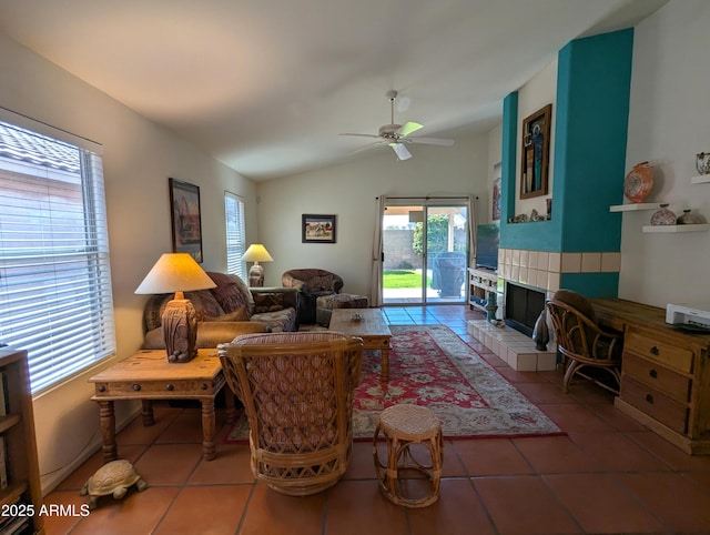 living room with tile patterned floors, a tiled fireplace, ceiling fan, and vaulted ceiling