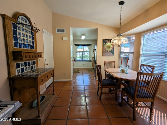 dining room featuring visible vents, tile patterned flooring, and vaulted ceiling