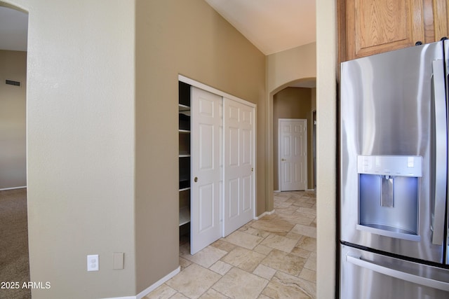1470 W Bartlett Way, Chandler, AZ 85248 - kitchen featuring stainless steel refrigerator with ice dispenser, arched walkways, light stone finish flooring, and baseboards