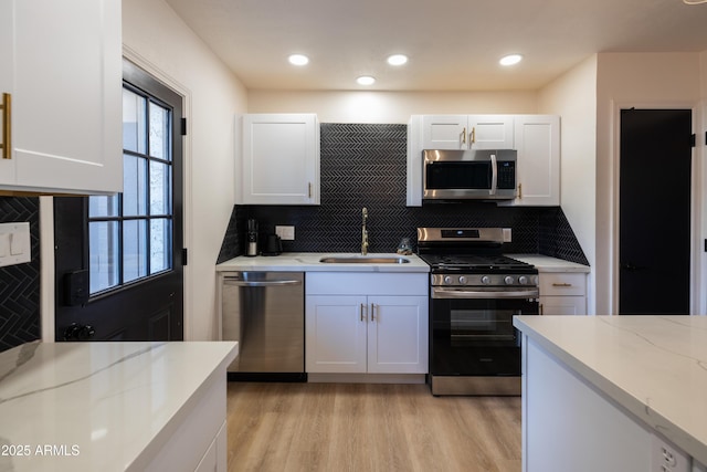 kitchen featuring appliances with stainless steel finishes, light wood-type flooring, white cabinets, and a sink