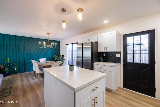 kitchen with a wealth of natural light, freestanding refrigerator, white cabinetry, and light wood finished floors