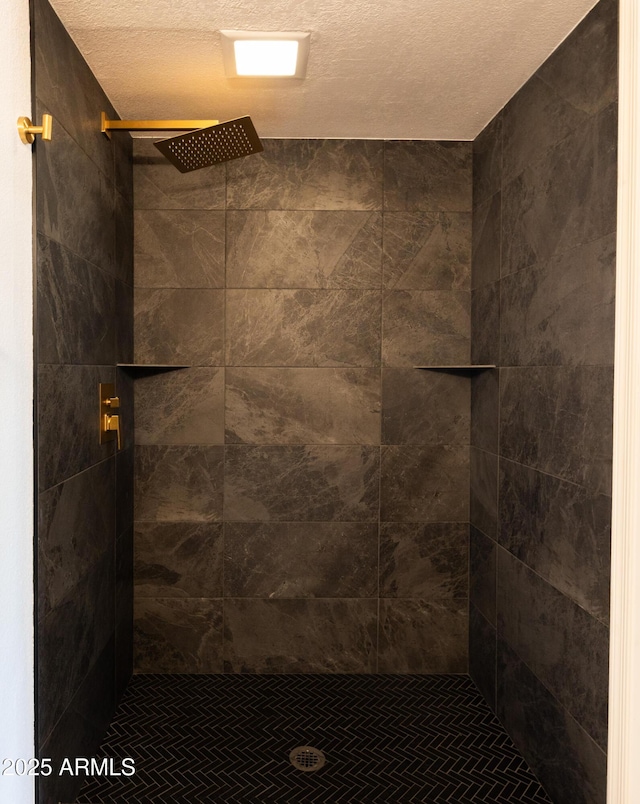 bathroom with a textured ceiling and tiled shower