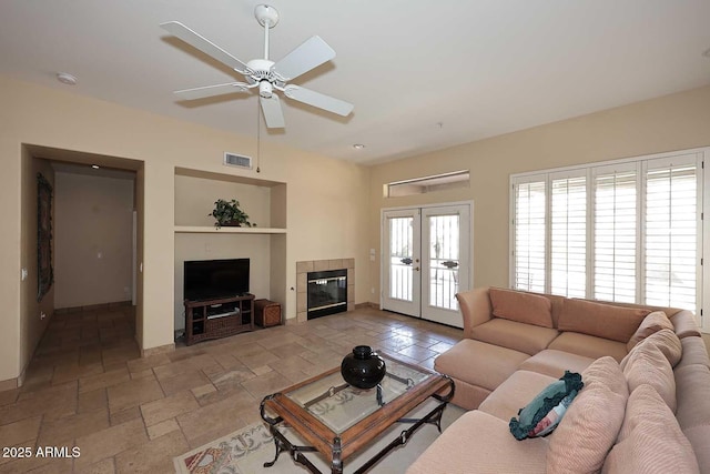 living room featuring visible vents, french doors, a fireplace, stone tile flooring, and a ceiling fan