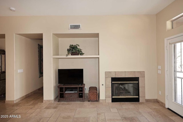 unfurnished living room featuring visible vents, baseboards, stone tile flooring, and a tile fireplace