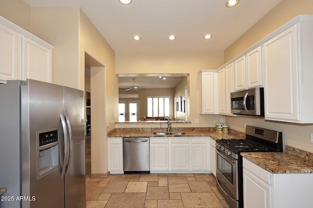 kitchen with recessed lighting, stainless steel appliances, stone tile flooring, white cabinetry, and a sink