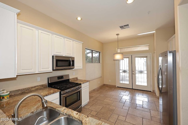 kitchen with visible vents, appliances with stainless steel finishes, stone tile flooring, white cabinetry, and a sink