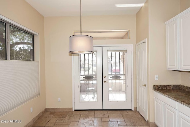 doorway to outside featuring french doors, baseboards, and stone tile flooring