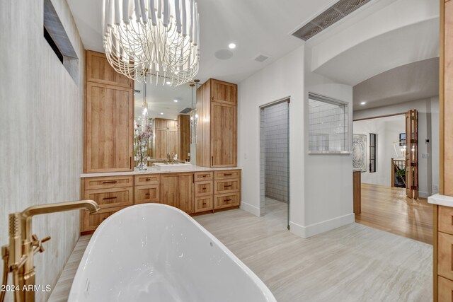 bathroom with a tub to relax in, vanity, wood-type flooring, and a chandelier