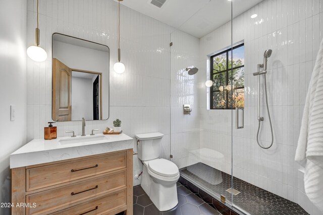 bathroom with vanity, toilet, tile walls, and walk in shower