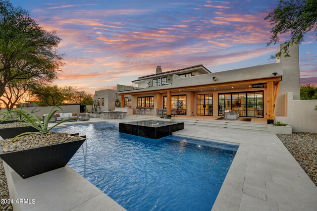 pool at dusk featuring a patio and pool water feature