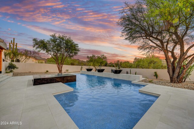 pool at dusk with a patio area