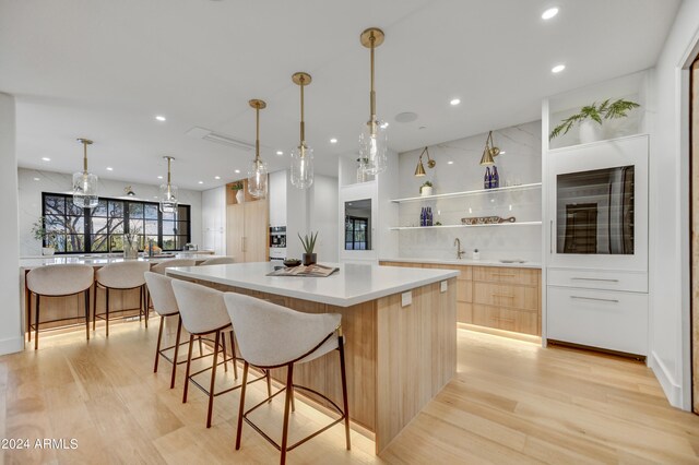 kitchen featuring light wood-type flooring, light brown cabinetry, a spacious island, and sink