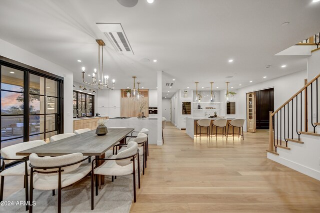 dining room with light wood-type flooring and a chandelier