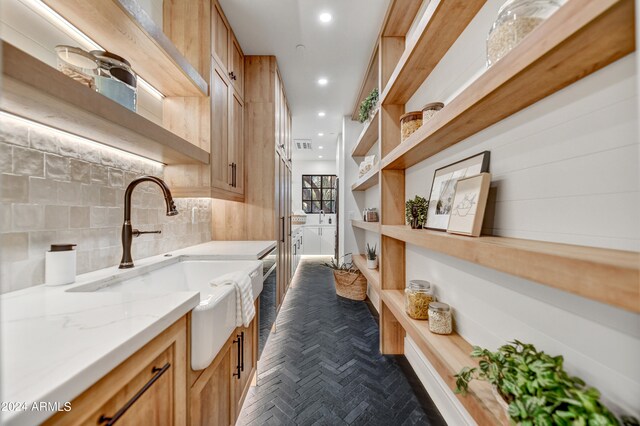 kitchen with light stone counters, sink, and decorative backsplash