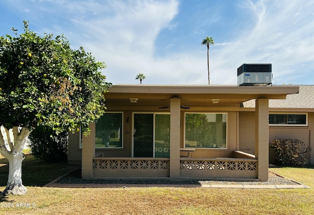 rear view of property featuring a yard, cooling unit, and a porch