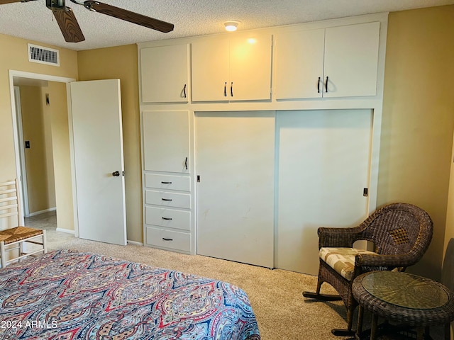 bedroom with light carpet, a textured ceiling, a closet, and ceiling fan