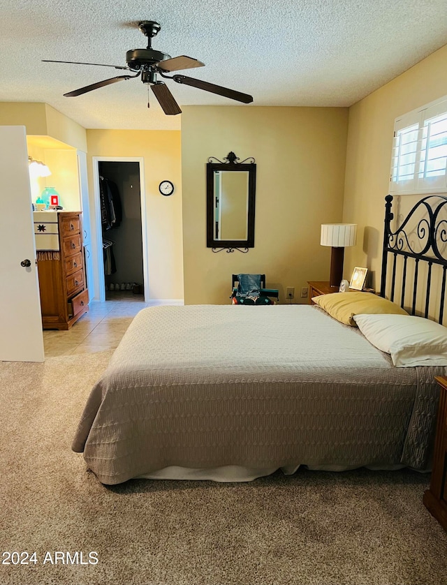 bedroom featuring ceiling fan, light tile patterned flooring, a spacious closet, and a textured ceiling