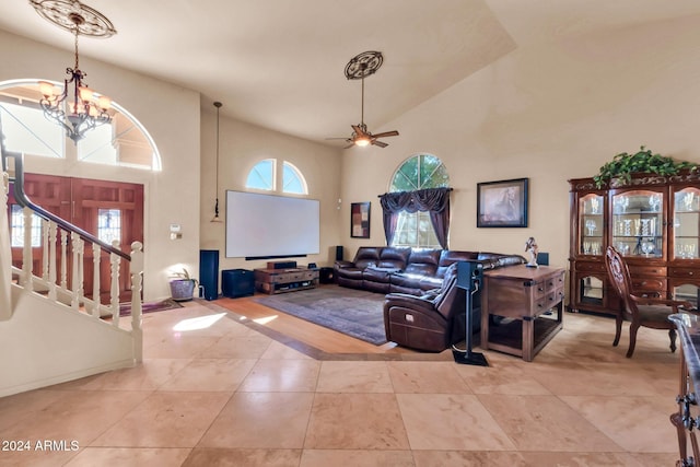 tiled living room featuring ceiling fan with notable chandelier and high vaulted ceiling