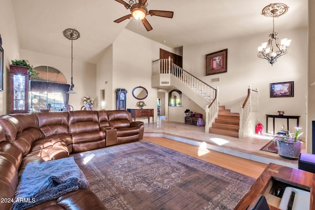 living room with a high ceiling, wood-type flooring, and ceiling fan with notable chandelier