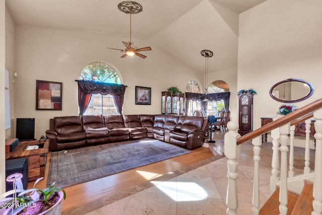 living room with ceiling fan with notable chandelier and high vaulted ceiling