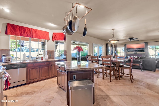 kitchen featuring sink, dishwasher, backsplash, a kitchen island, and light tile patterned flooring