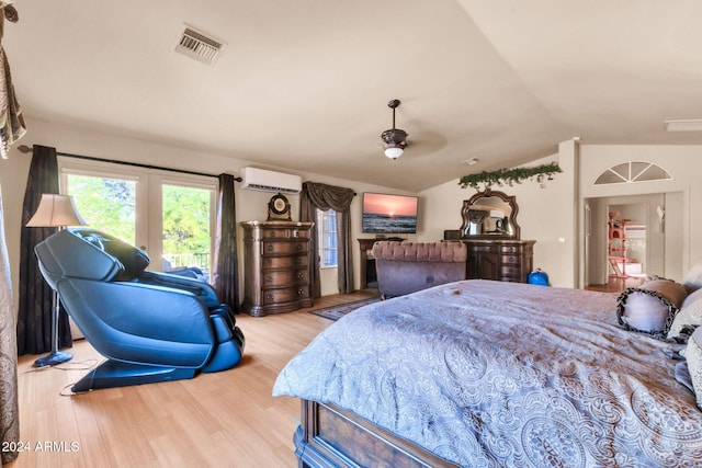 bedroom featuring lofted ceiling, a wall mounted AC, and light wood-type flooring