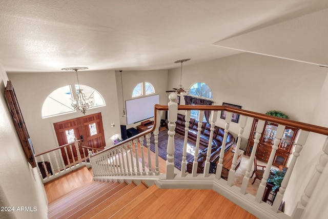 stairs featuring an inviting chandelier, hardwood / wood-style floors, and a high ceiling