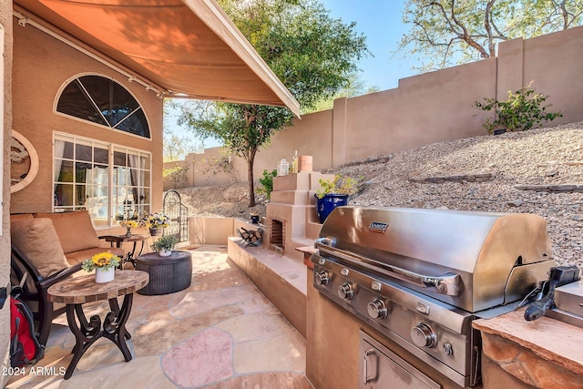 view of patio featuring an outdoor fireplace, exterior kitchen, and area for grilling