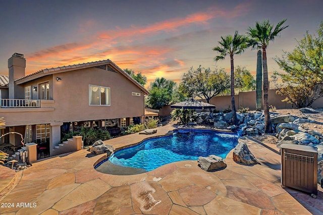 pool at dusk with a patio area