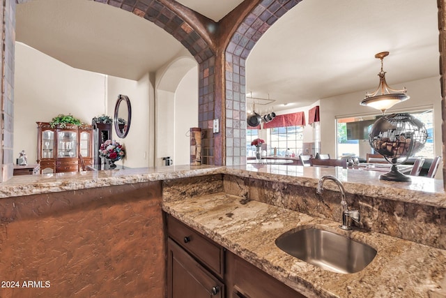 kitchen featuring pendant lighting, sink, and light stone countertops