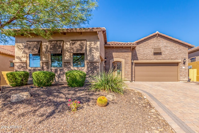 view of front of property featuring a tile roof, decorative driveway, and a garage