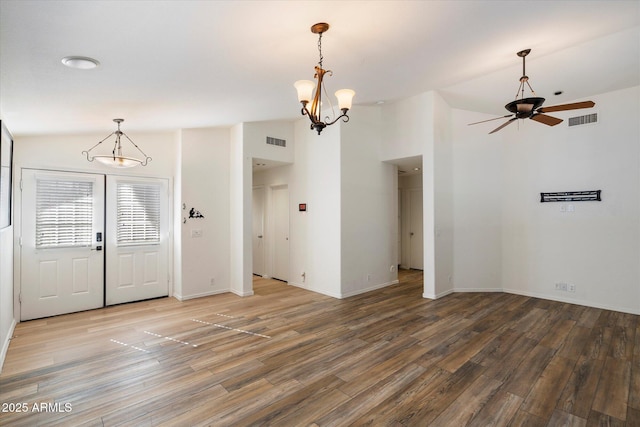 entrance foyer with lofted ceiling, ceiling fan with notable chandelier, and hardwood / wood-style flooring