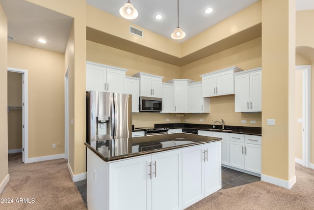 kitchen with carpet floors, sink, a kitchen island, white cabinetry, and appliances with stainless steel finishes