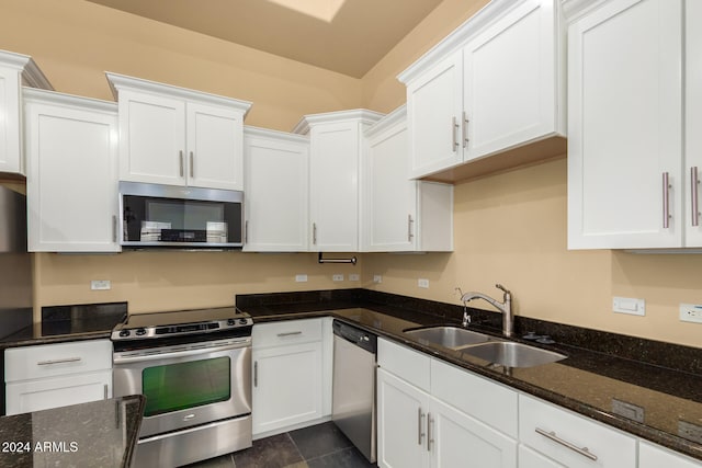 kitchen with dark stone counters, white cabinetry, appliances with stainless steel finishes, and sink